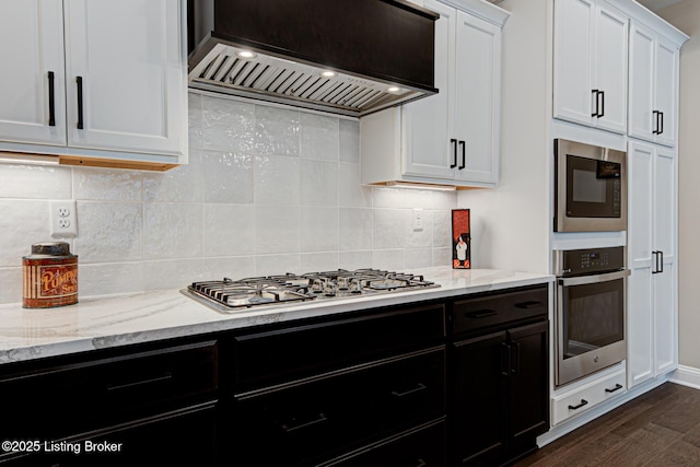 kitchen featuring premium range hood, white cabinetry, light stone countertops, and stainless steel appliances