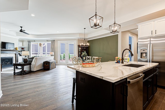 kitchen featuring dark wood-style flooring, a raised ceiling, stainless steel appliances, and a sink