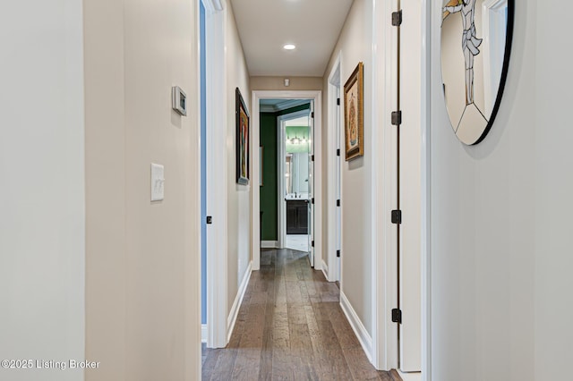 corridor featuring wood-type flooring, baseboards, and recessed lighting