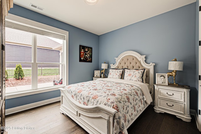 bedroom with visible vents, baseboards, and hardwood / wood-style floors