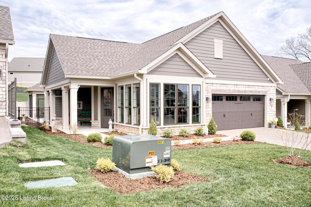exterior space with roof with shingles, driveway, stone siding, a front yard, and a garage