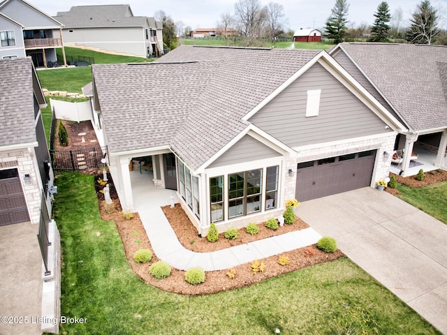 view of front of house featuring a shingled roof, fence, concrete driveway, and a front yard