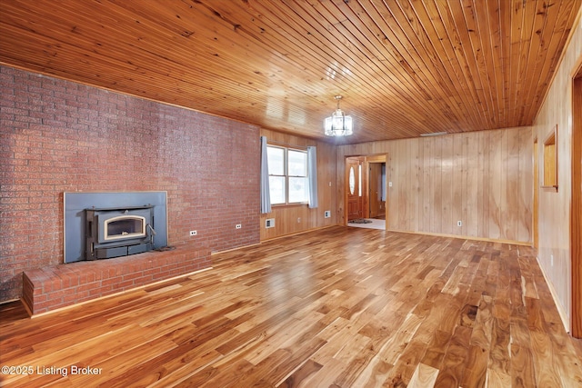 1109 Holly Ave, Louisville, KY 40118 - unfurnished living room featuring wood finished floors, wooden ceiling, wood walls, and a wood stove