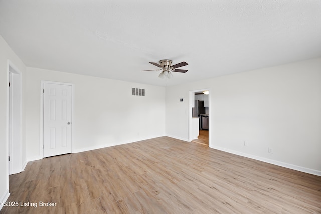 empty room with baseboards, a ceiling fan, visible vents, and light wood-style flooring