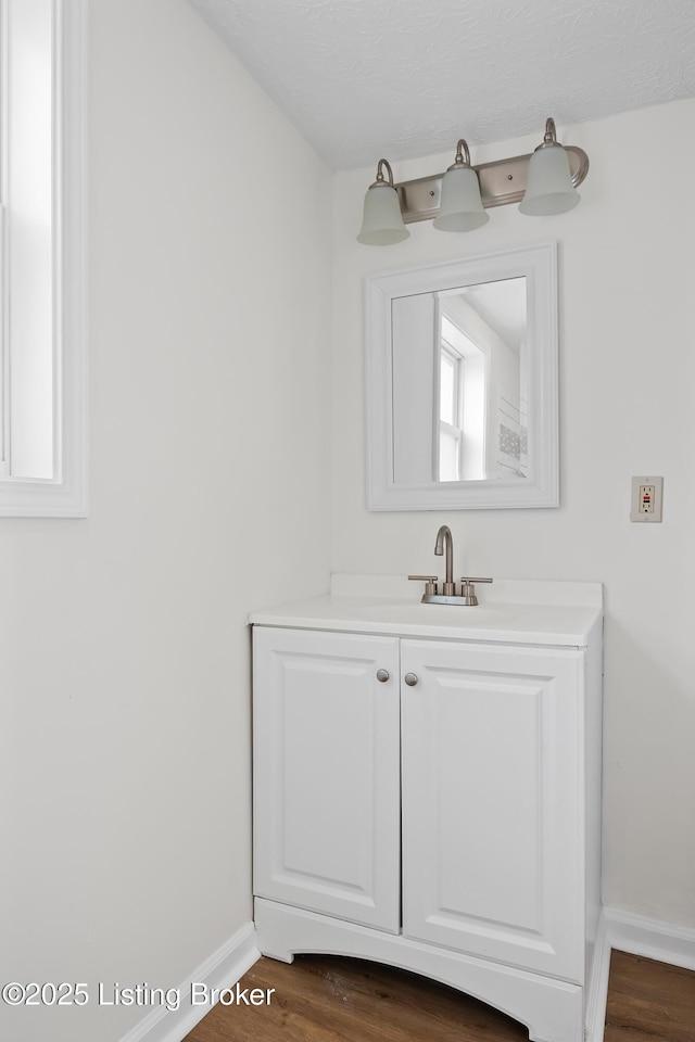 bathroom with wood finished floors, vanity, and baseboards