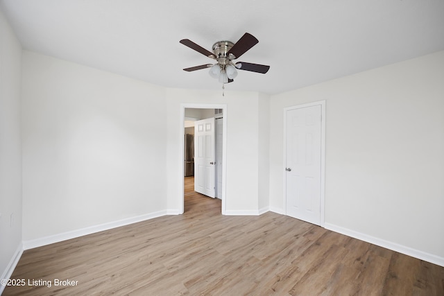 unfurnished bedroom with freestanding refrigerator, baseboards, light wood-style floors, and ceiling fan