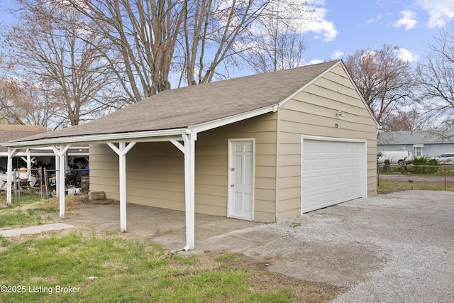 garage with fence, aphalt driveway, and a detached garage