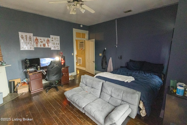 bedroom featuring ceiling fan, visible vents, wood finished floors, and an AC wall unit