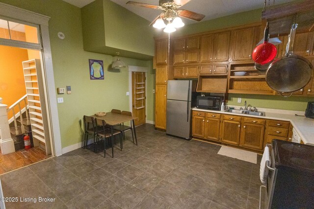 kitchen featuring light countertops, stainless steel appliances, a sink, a ceiling fan, and brown cabinetry