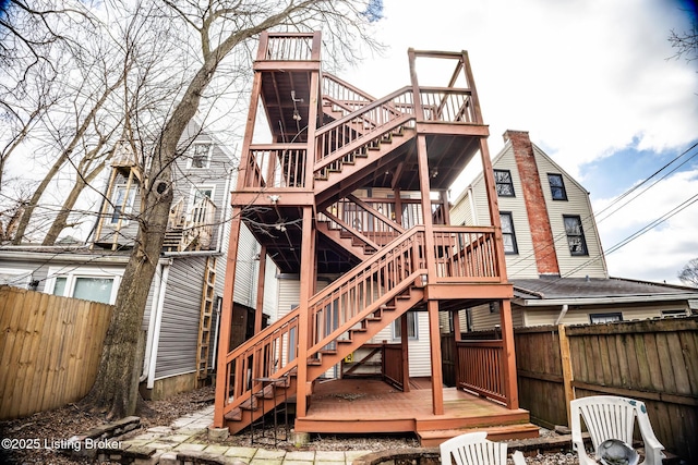 rear view of house featuring stairway, fence, and a wooden deck
