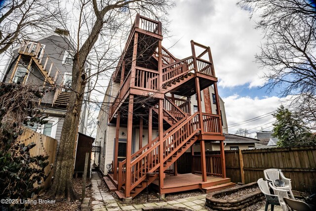back of house featuring stairs, fence, an outdoor fire pit, and a deck