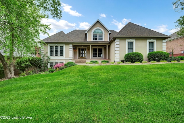 view of front of home featuring a front lawn, stucco siding, covered porch, and roof with shingles