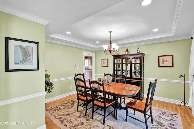 dining area with light wood-type flooring, a chandelier, a tray ceiling, baseboards, and recessed lighting