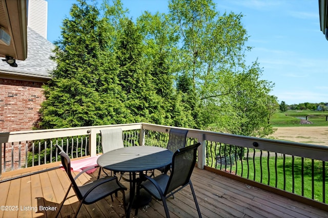deck with outdoor dining area and a lawn