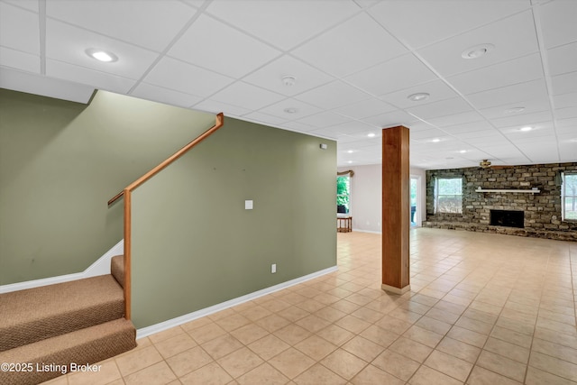 unfurnished living room featuring a fireplace, baseboards, a drop ceiling, stairs, and recessed lighting
