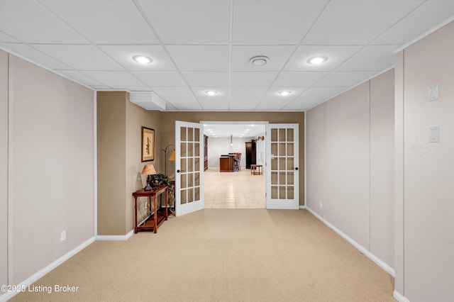 below grade area with french doors, recessed lighting, light colored carpet, baseboards, and a drop ceiling
