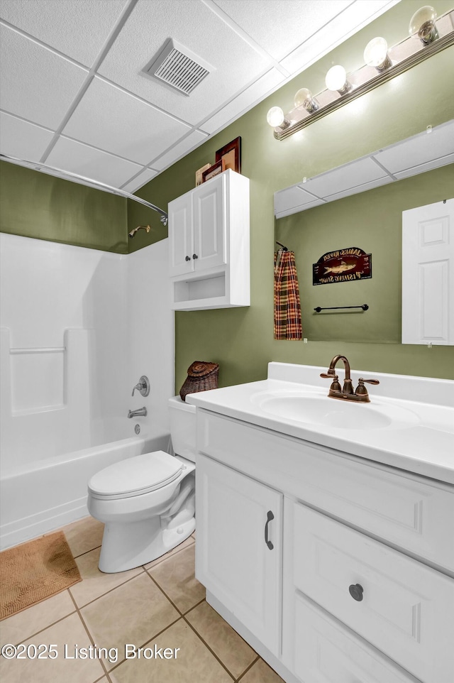 bathroom featuring a paneled ceiling, tile patterned floors, toilet, vanity, and tub / shower combination