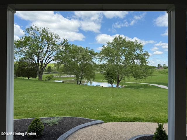 view of green lawn featuring a water view