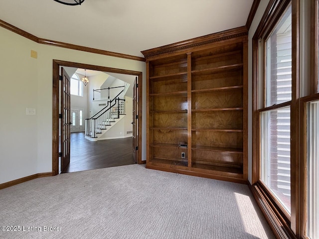 spare room featuring ornamental molding, stairs, dark carpet, and baseboards