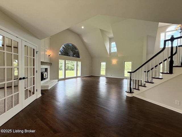 unfurnished living room featuring high vaulted ceiling, dark wood-style flooring, french doors, stairway, and baseboards