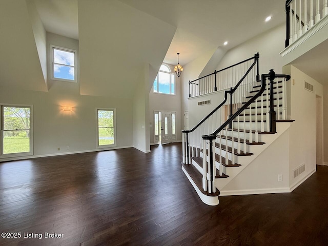 entryway featuring a chandelier, high vaulted ceiling, dark wood-style flooring, baseboards, and stairs