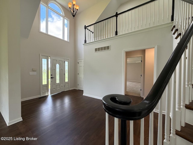 entryway with a high ceiling, healthy amount of natural light, a chandelier, and stairs