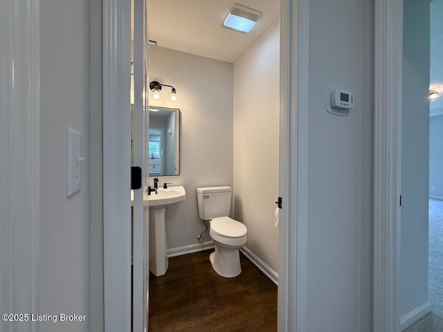 bathroom featuring toilet, wood finished floors, and baseboards