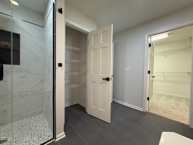 full bathroom with a stall shower, a spacious closet, tile patterned flooring, and baseboards