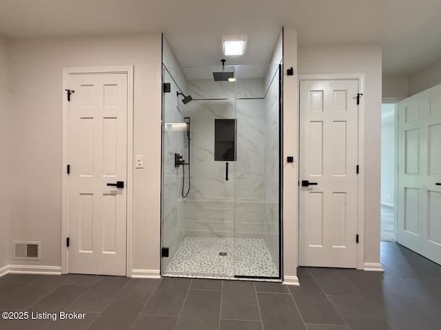 bathroom featuring a marble finish shower, tile patterned floors, and baseboards