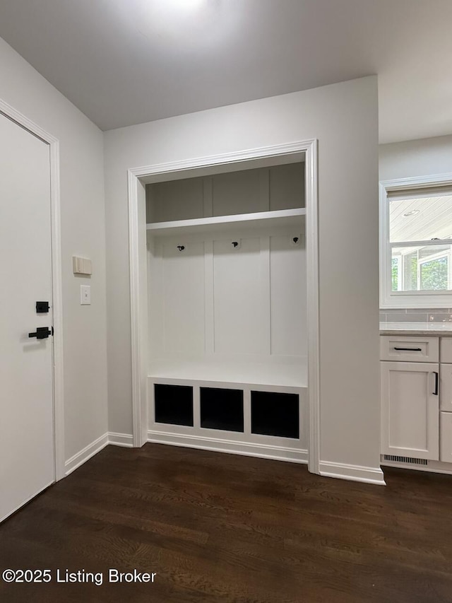 mudroom with dark wood finished floors and baseboards