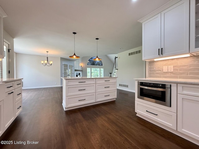kitchen featuring dark wood-type flooring, decorative backsplash, baseboards, and a chandelier