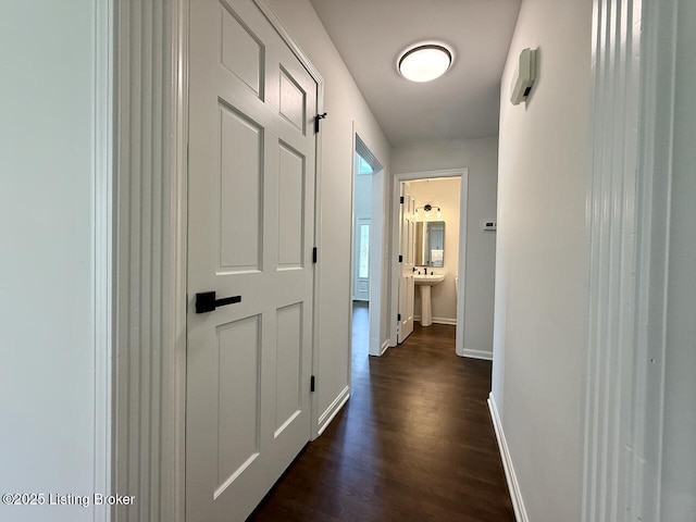 hallway featuring dark wood-type flooring and baseboards