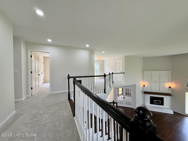hallway with an upstairs landing, baseboards, recessed lighting, and carpet