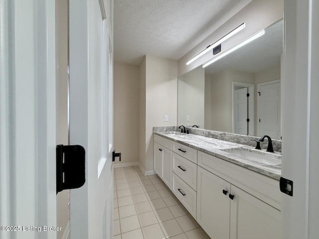 full bathroom with a textured ceiling, tile patterned flooring, double vanity, and baseboards