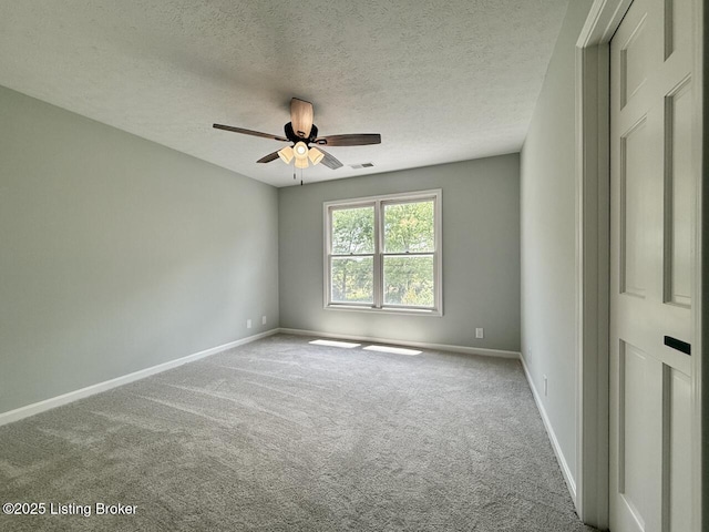 spare room with carpet flooring, baseboards, ceiling fan, and a textured ceiling