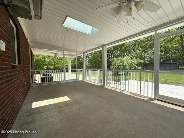 unfurnished sunroom with a ceiling fan, a skylight, and plenty of natural light