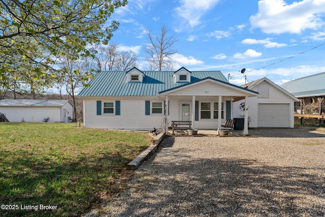 view of front of property with an outbuilding, metal roof, gravel driveway, a porch, and a garage