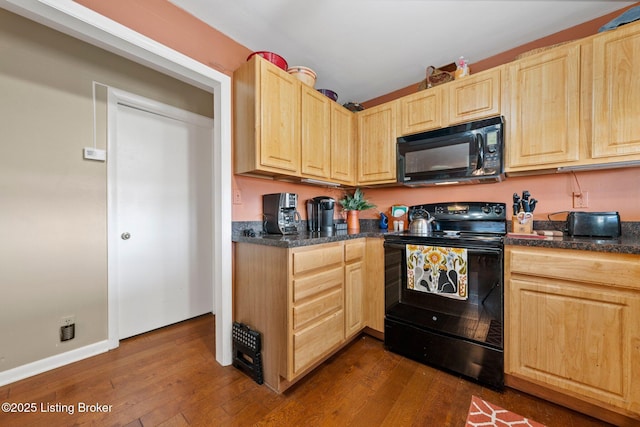 kitchen featuring dark wood-style floors, light brown cabinetry, black appliances, and baseboards