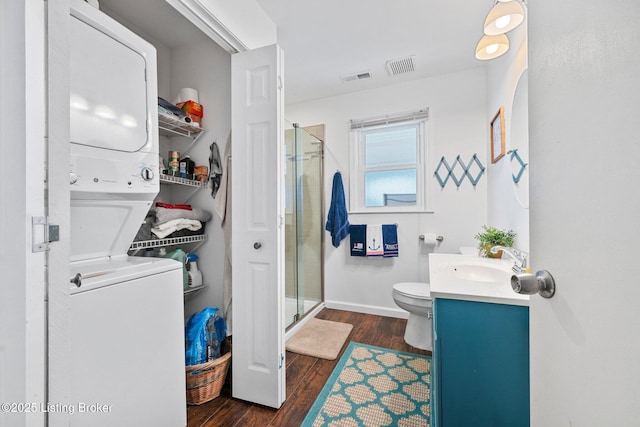 bathroom with a stall shower, visible vents, stacked washer / drying machine, and vanity