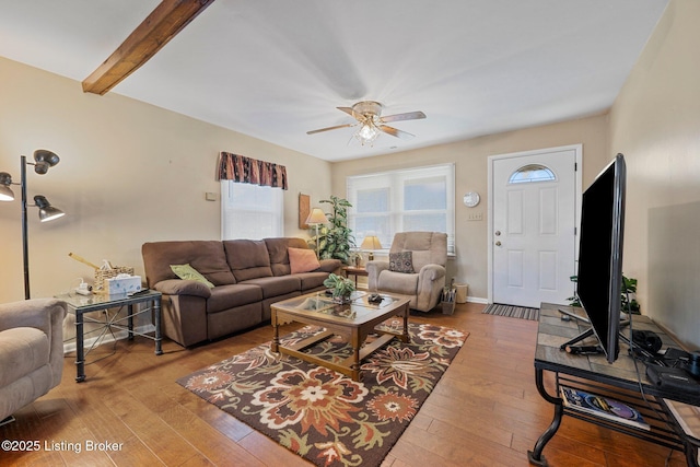 living room featuring baseboards, beamed ceiling, ceiling fan, and hardwood / wood-style flooring