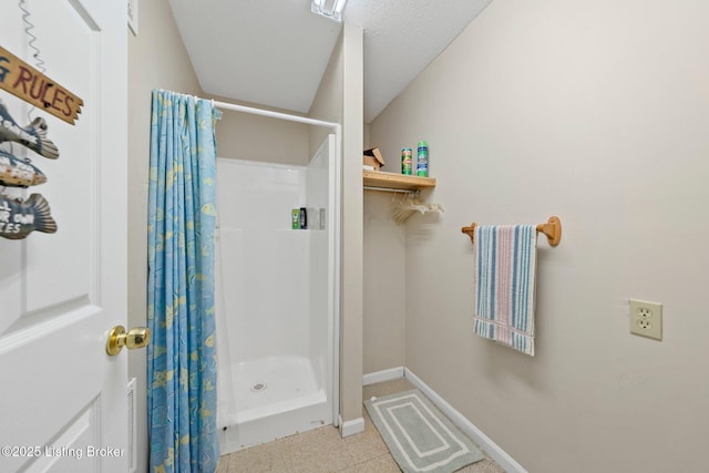 bathroom with baseboards and a shower stall