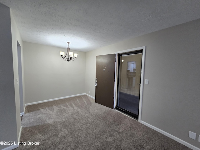 unfurnished room featuring carpet flooring, an inviting chandelier, baseboards, and a textured ceiling