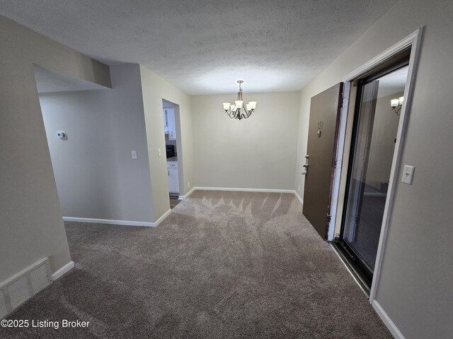 carpeted empty room with a textured ceiling, visible vents, baseboards, and a chandelier