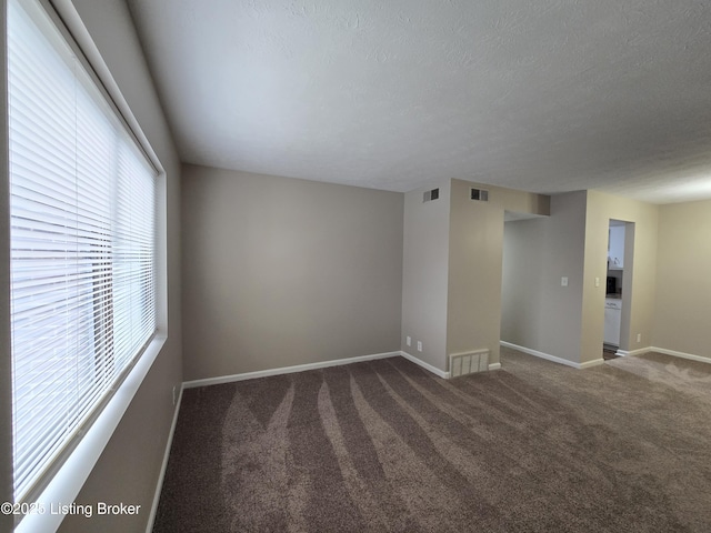 carpeted spare room featuring a textured ceiling, baseboards, and visible vents