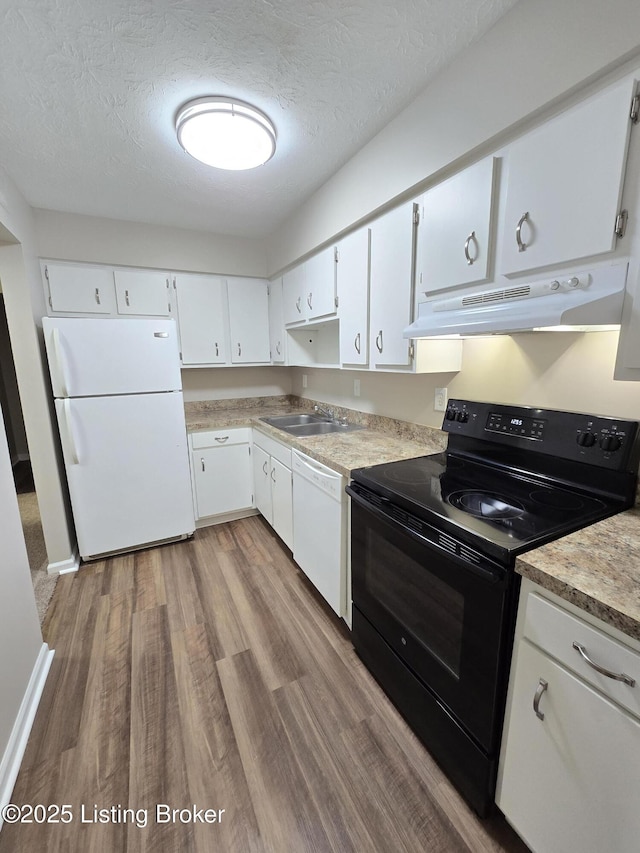 kitchen featuring white appliances, wood finished floors, under cabinet range hood, white cabinetry, and a sink