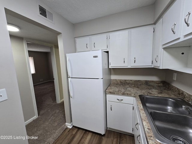 kitchen with white cabinetry, visible vents, a sink, and freestanding refrigerator