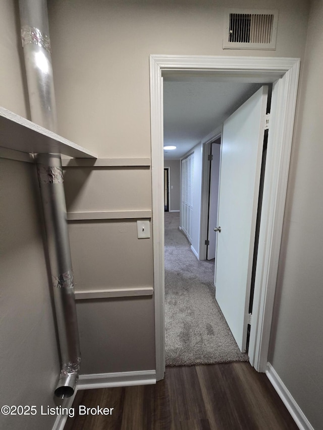 hallway featuring baseboards, visible vents, and wood finished floors