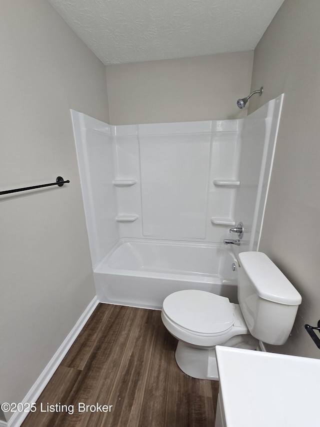 full bathroom featuring shower / bath combination, toilet, baseboards, a textured ceiling, and wood finished floors