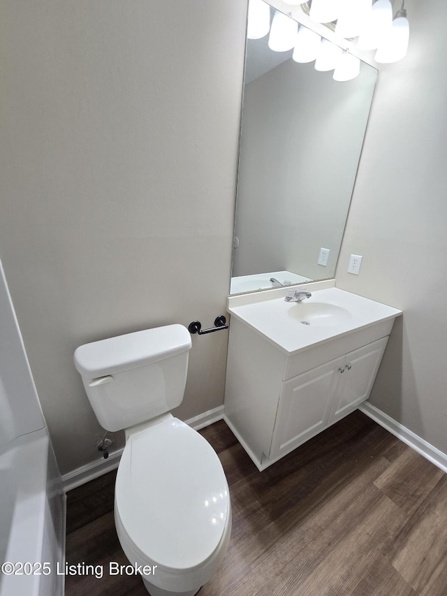 bathroom featuring toilet, wood finished floors, baseboards, and vanity