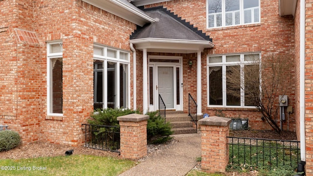 doorway to property with brick siding and fence